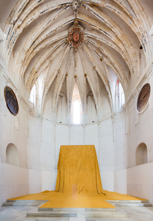In einer Installationsansicht von Delcy Morelos umschließt eine kuppelartige Architektur einen Altarraum in dessen Nische ein weites gelbes Tuch über einen nicht mehr sichtbaren Altar gebreitet ist