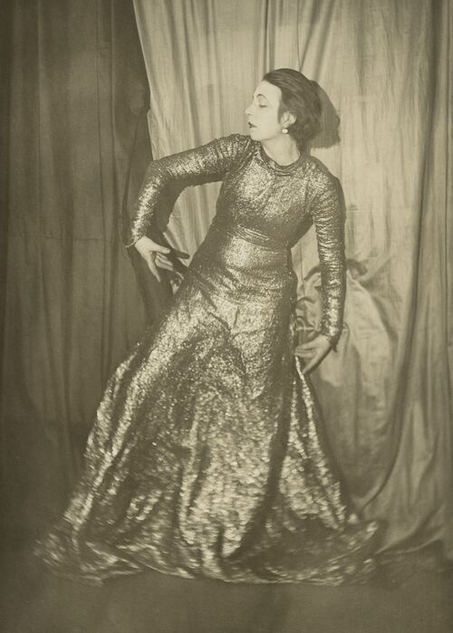 Selbstportrait der Künstlerin Marta-Astfalck-Vietz als Schwarz-Weiß-Fotografie. Sie steht in einem langen glitzernden Kleid in einer tänzerischen Pose vor Vorhängen.