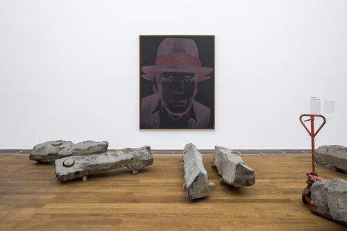 Ein von Andy Warhol gemaltes Porträt zeigt Joseph Beuys. Es hängt an der Wand vor dem Werk "Das ist das Ende des 20. Jahrhunderts" von Beuys. Dieses besteht aus 44 Steinen die von einem erloschenen Vulkan abgetragen wurden.