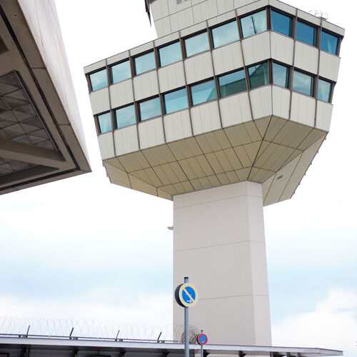 Ein Blickwinkel von unten auf den markanten, mehrstöckigen und weiß gestrichenen Tower des ehemaligen Flughafens Tegel.