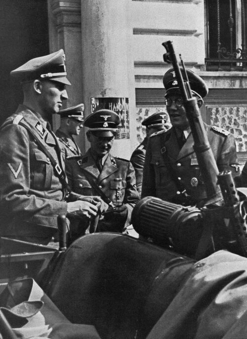 Historische Aufnahme von Reinhard Heydrich vor dem Quartier der Einsatzgruppe II im Gespräch mit weiteren Personen der Einsatzgruppe.