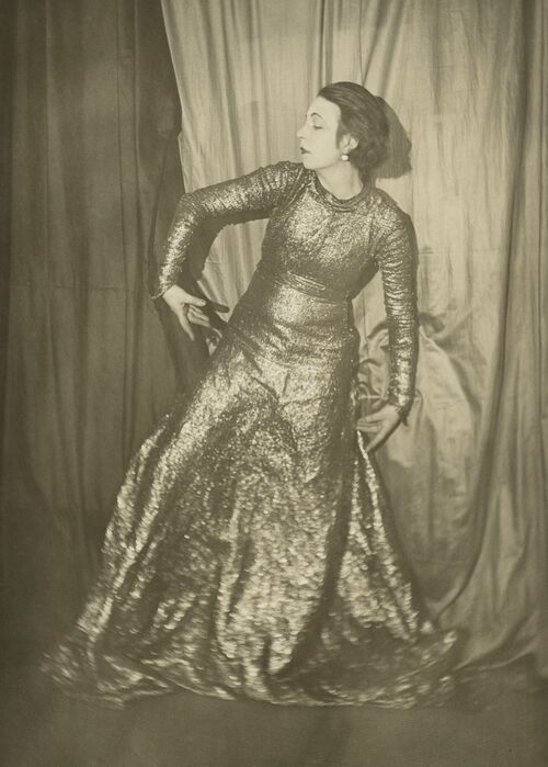 Selbstportrait der Künstlerin Marta-Astfalck-Vietz als Schwarz-Weiß-Fotografie. Sie steht in einem langen glitzernden Kleid in einer tänzerischen Pose vor Vorhängen.