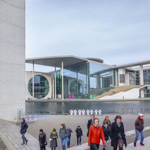 A group of people in the government district in Berlin move up a flight of stairs in front of the Spree.